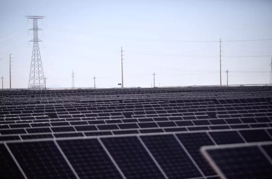 Campo de paneles solares con torres de distribución eléctrica de fondo