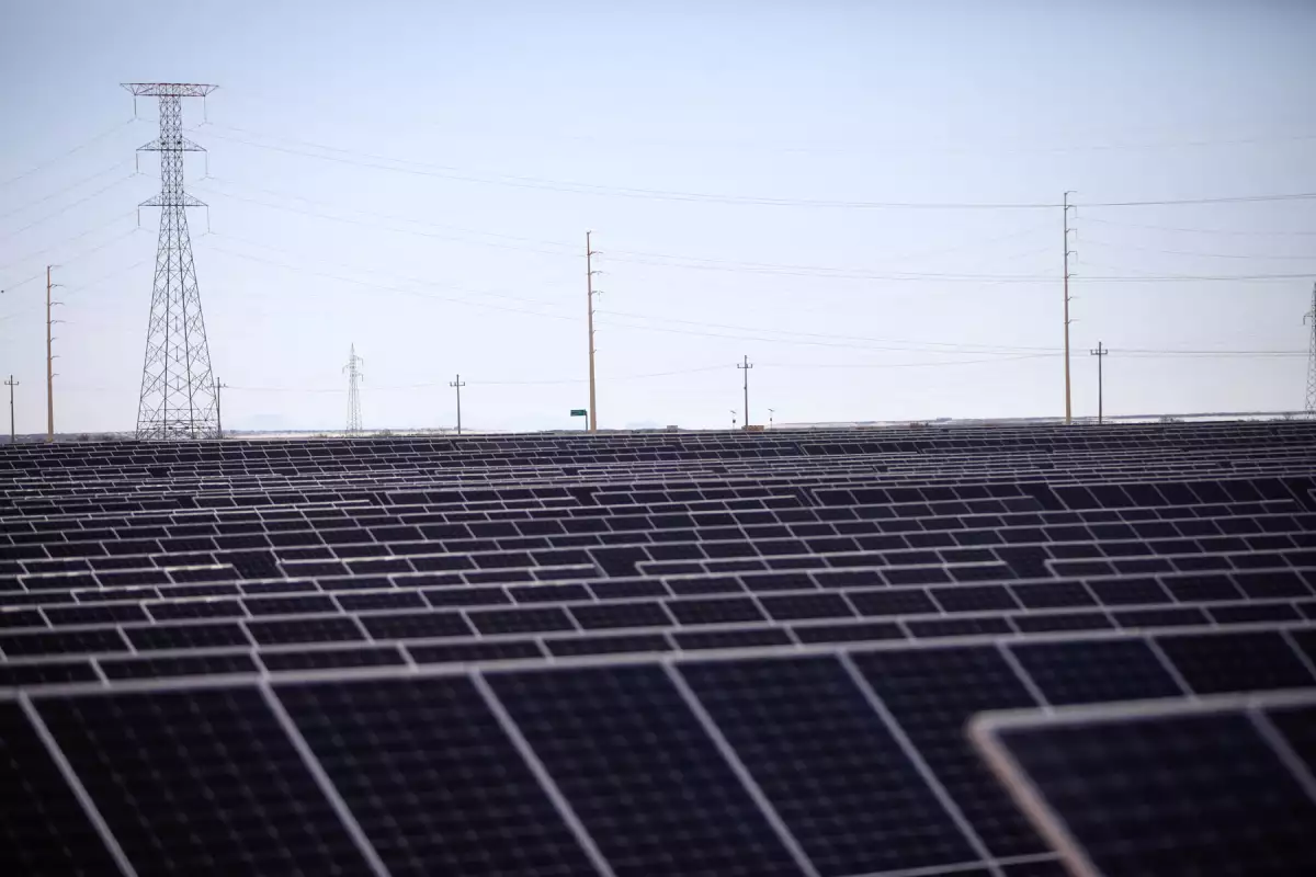 Campo de paneles solares con torres de distribución eléctrica de fondo